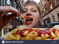 young-woman-eats-french-fries-with-ketchup-AX5C0J.jpg